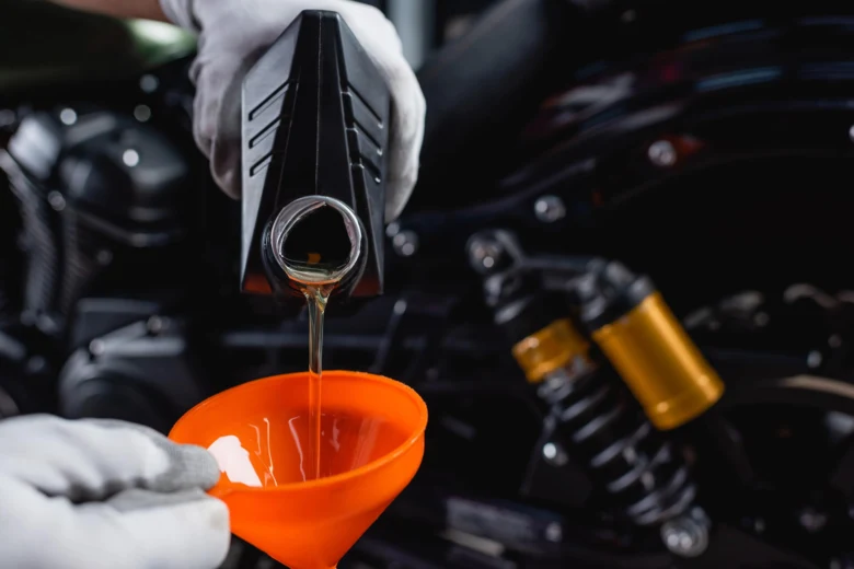 Lidář nalévá syntetický olej do motorky pomocí oranžového lejna.