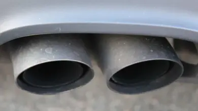 Dvě černé výfukové trubicí automobilu pod šedým nárazníkem.