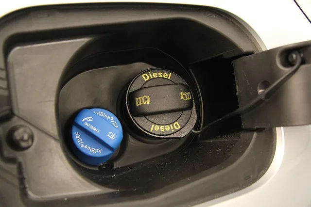 Modrý víčko AdBlue a černé Diesel v nádrži vozidla.