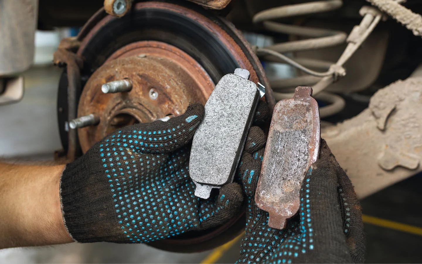 Mechanik porovnává nový a opotřebovaný brzdový čepel u kola.