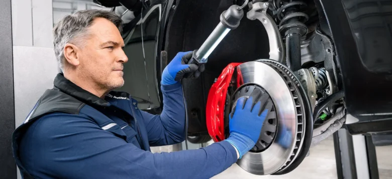 Mechanik opravuje brzdný systém automobilu na zvedáku.