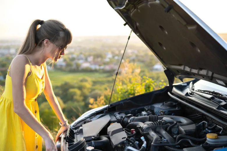 Žena kontroluje motor vozu s otevřenou kapotou.