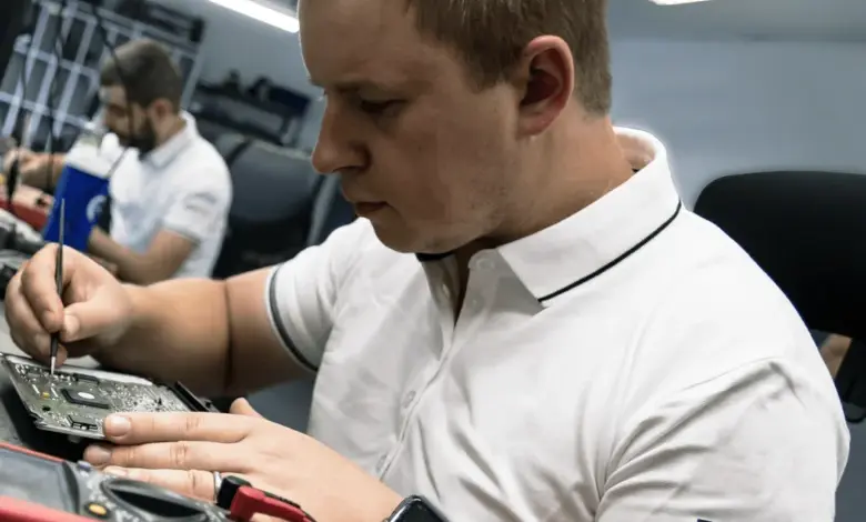 Mechanik opravuje elektroniku multimetrem v dílně.