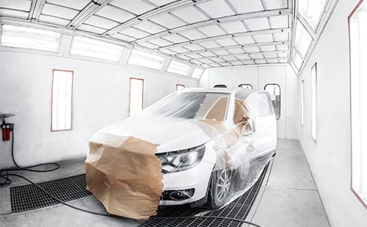 Bílé auto v lakovárně připraveno na profesionální malování nárazníku.