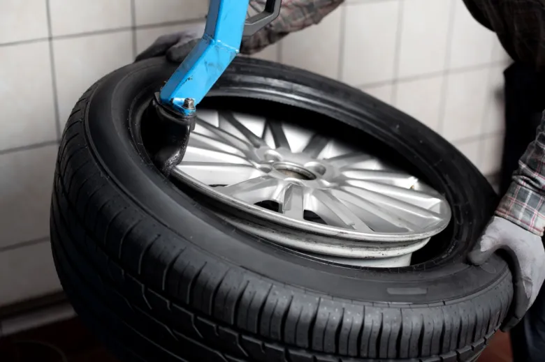 Montáž pneumatiky pomocí mechanického nástroje v dílně