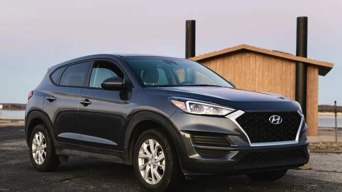 Tmavý SUV automobil značky Hyundai zaparkovaný venku.