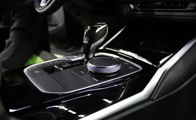 Interiér auta s automatem ukazující páku převodovky a tlačítko parkovací brzdy.