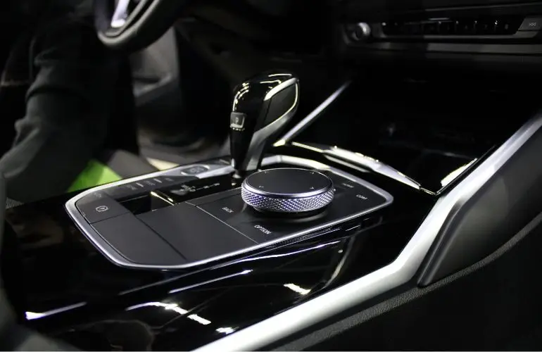 Interiér auta s automatem ukazující páku převodovky a tlačítko parkovací brzdy.