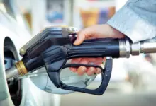 Ruka drží čerpadlo při plnění auta benzínem na benzinové stanici.