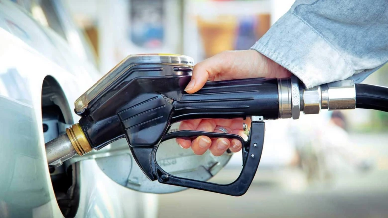 Ruka drží čerpadlo při plnění auta benzínem na benzinové stanici.