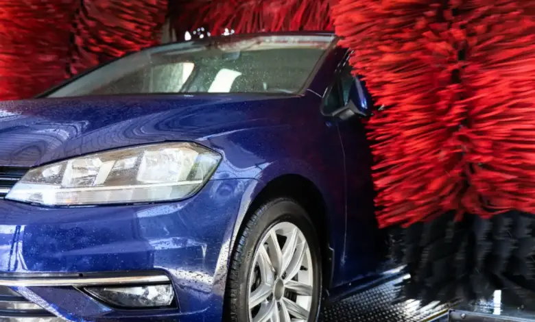 Modré auto v samoobslužné myčce s červenými kartáči.