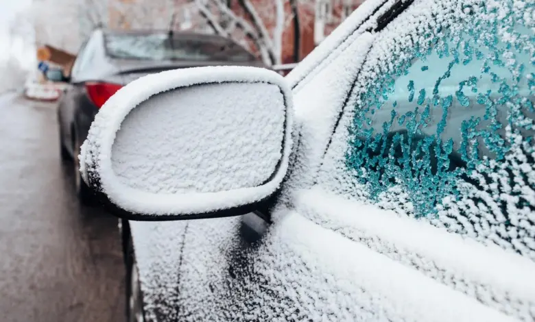 Zasněžené boční zrcátko automobilu v zimních podmínkách.