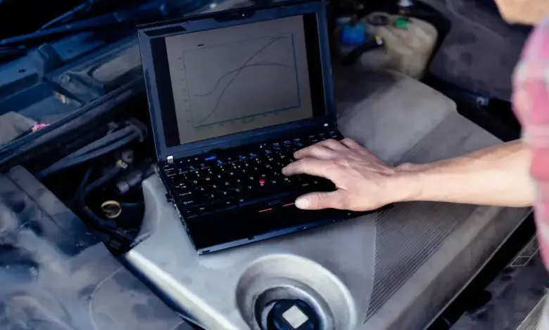 Laptop s grafy na motoru auta při diagnostice pro chiptuning