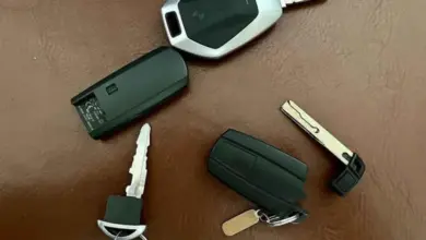 Různé typy klíčů k autu s dálkovým ovládáním na hnědé podložce.