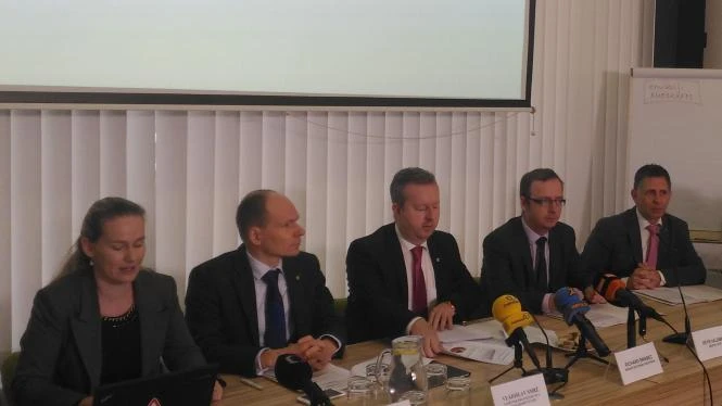 Panelist na konferenci s mikrofony, ne technický průkaz.