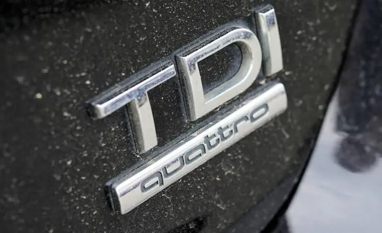 Bližší záběr na stříbrné logo TDi Quattro na černém karoserii.