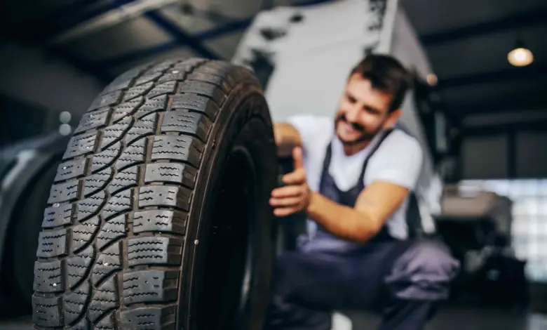 Mechanik drží pneumatiku v dílně pro montáž