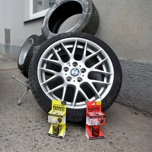 Kolo s diskem, zvedák a krabice na asfaltu u stěny.