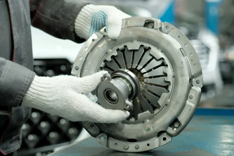 Mechanik drží spojku automobilu pro kontrolu nebo výměnu.