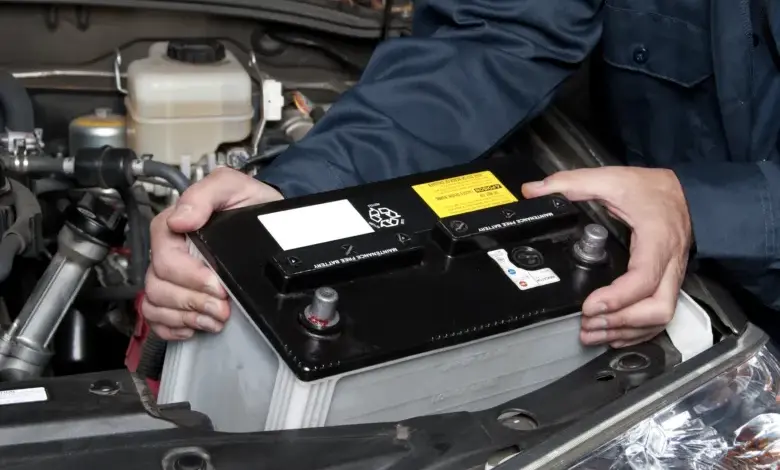Mechanik instaluje novou autobaterii do motorového prostoru vozu.
