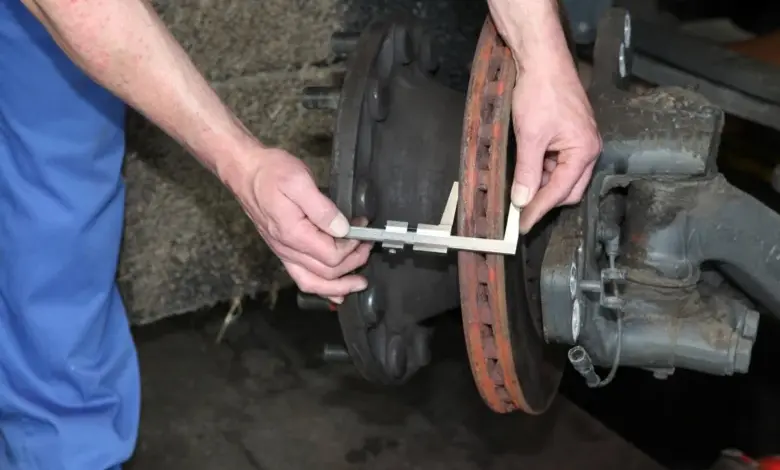 Mechanik měří tloušťku brzdového kotouče kalibrem.