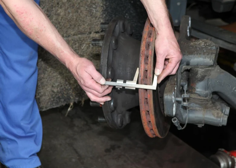 Mechanik měří tloušťku brzdového kotouče kalibrem.