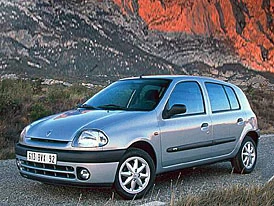 Stříbrný hatchback zaparkovaný na štěrkové cestě před skalami.