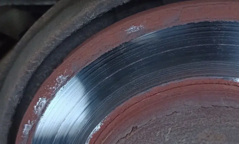 Zblízka poškozený brzdový disk s výkoly a rezem způsobující hučení.