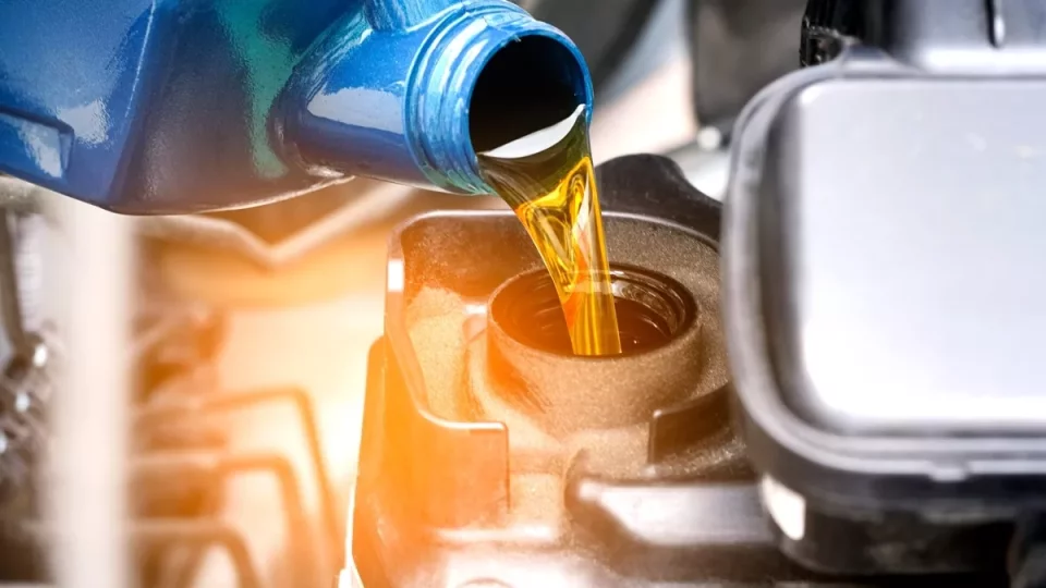 Zlatý olej se nalévá do otvoru pro výměnu oleje v automobilovém motoru.