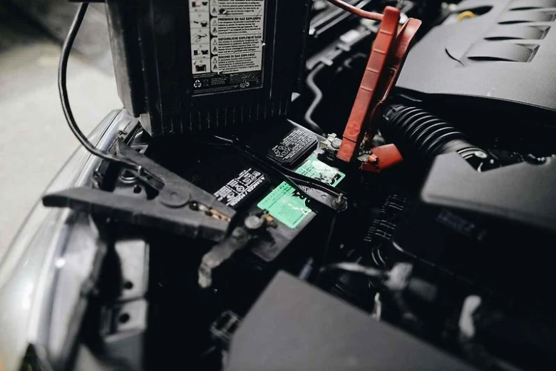 Připojení kabelů k novému autobaterii v motorovém prostoru