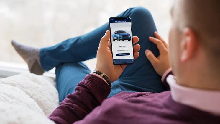 Muž používá aplikaci pro auto na mobilu v pohodlné poloze.