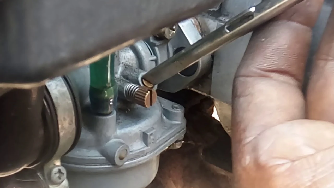 Ruční úprava karburátoru šroubovákem pro nastavení motoru.