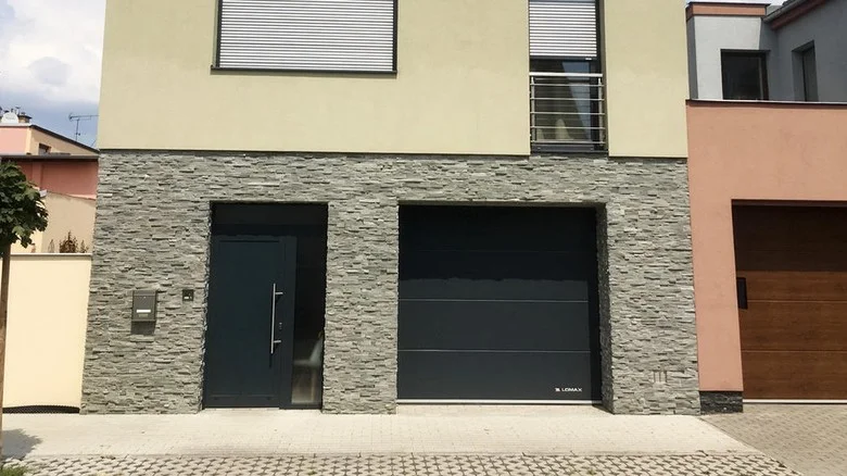 Moderní garážová vrata vedle vchodu na fasádě domu