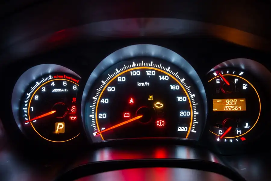 Palubní deska s rychloměrem a varovnými ikonami v automobilu.