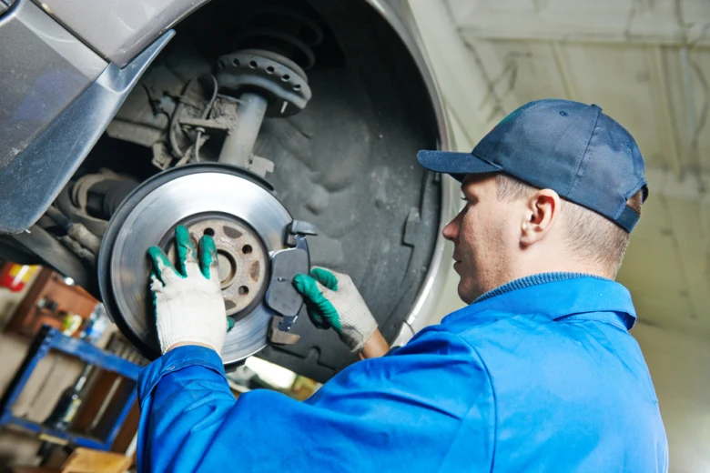 Mechanik opravuje brzdný kotouč u kola automobilu.