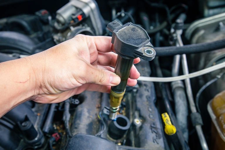 Ruční odstranění špinavé zapalovací cívky z motoru.