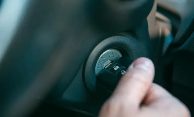 Ruka otáčí klíč v zapalování auta při startu motoru.