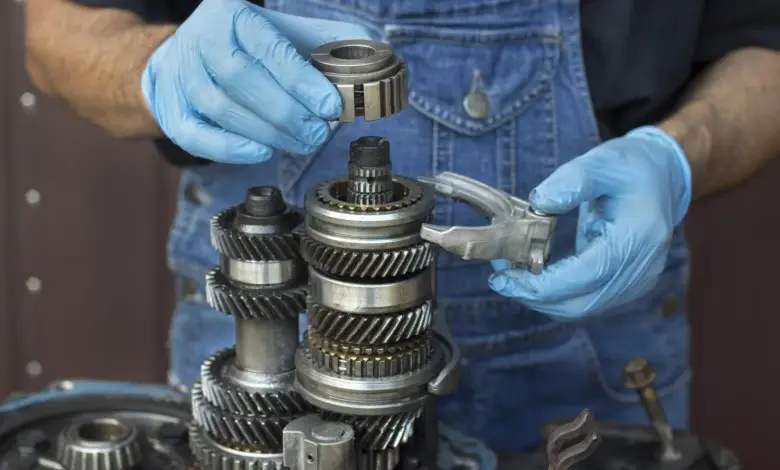 Mechanik opravuje převodovku s ozubenými koly pro řazení.