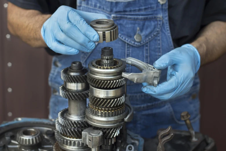 Mechanik opravuje převodovku s ozubenými koly pro řazení.