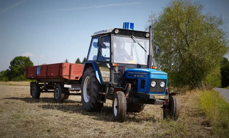 Modrý traktor s přívěsem na poli