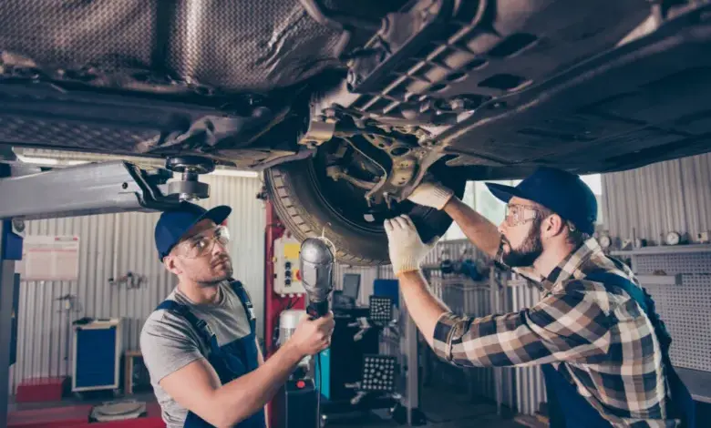 Mechanici opravují podvozek auta v dílně.