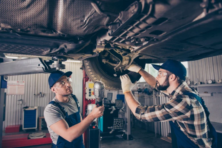 Mechanici opravují podvozek vozu pro odstranění vůle v řízení.