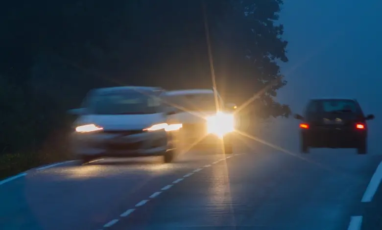 Autoběh s zapnutými světlomety v noci na silnici.