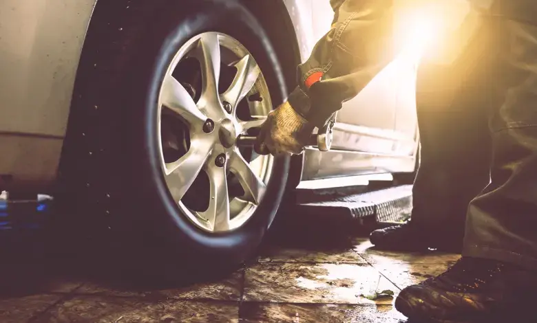 Mechanik montuje pneumatiku na automobilu v dílně.