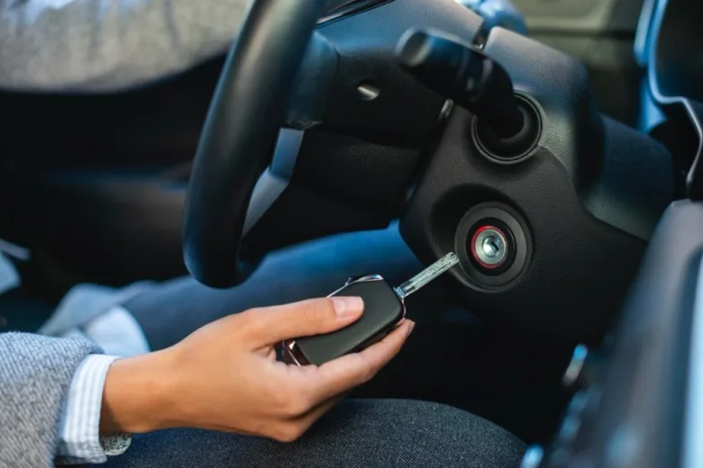 Ruka vkládá klíč do zapalování v autě s automatikou.