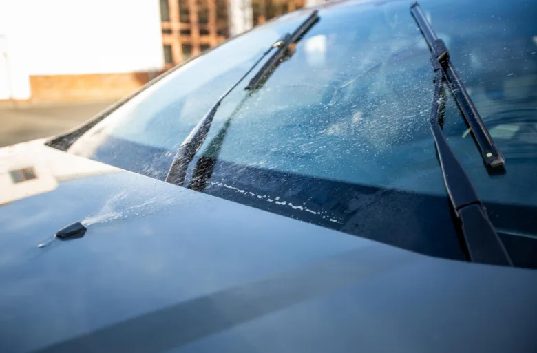 Přední sklo automobilu s ostřikovači, nikoliv zadním oknem.