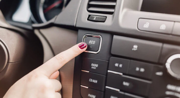 Prst tlačí na tlačidlo ECO v automobilu.