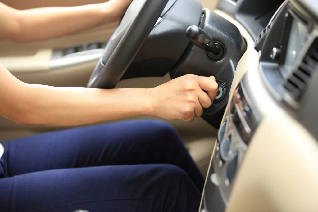 Osoba zapíná auto klíčem u volantu.