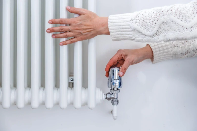 Ruka otáčí ventilátor na radiátoru při údržbě topení.