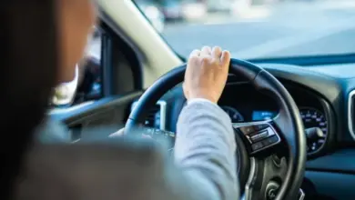 Osoba řídí automobil s volantem v rukou.